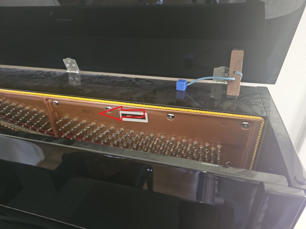 A Hailun upright piano with the lid open, revealing the serial number location.