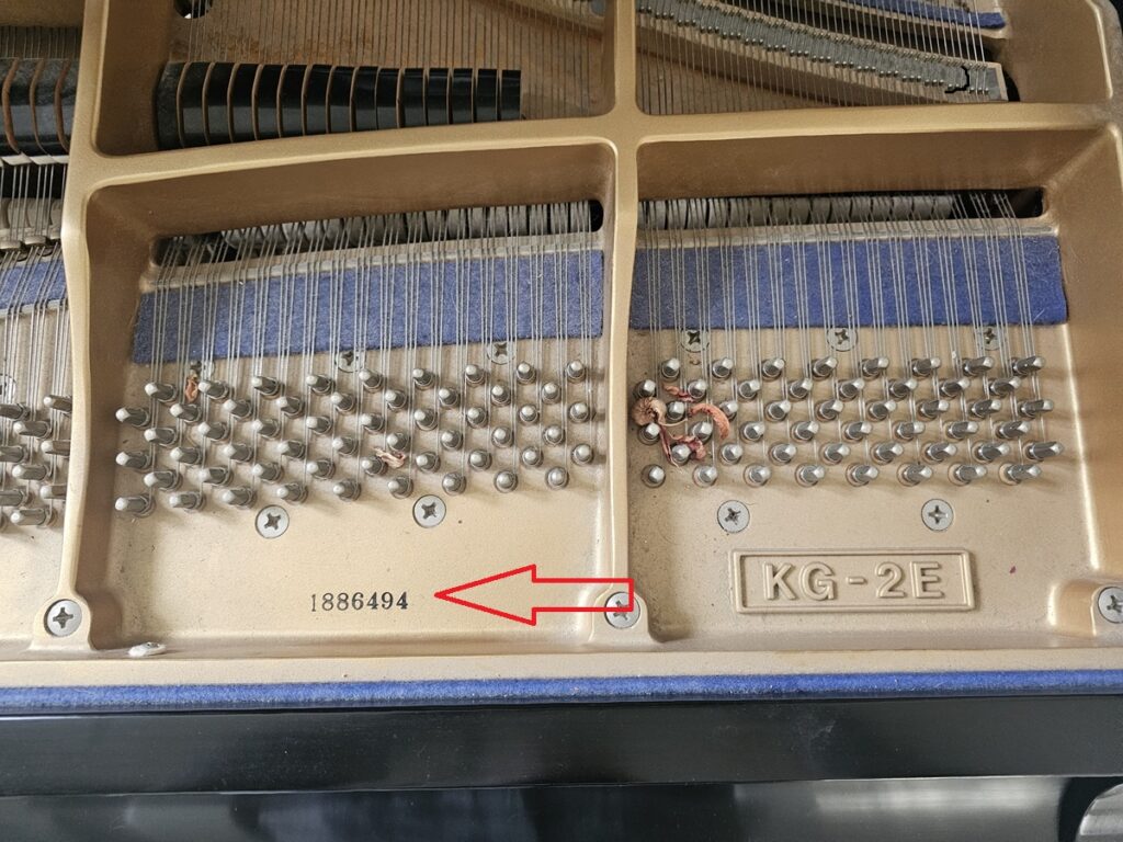 A Kawai KG-2E grand piano with the lid open, revealing the serial number location.