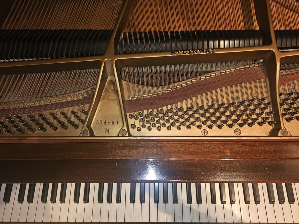 A Steinway & Sons grand piano with the lid open, revealing the serial number location.