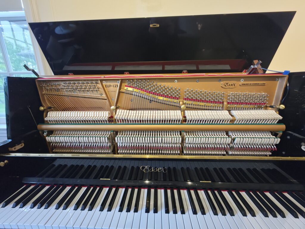 Essex upright piano with the lid open and front removed, revealing the serial number location.