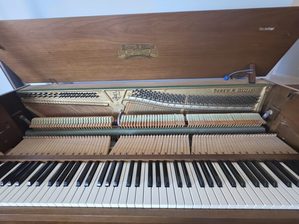 A Henry F. Miller spinet piano opened up.
