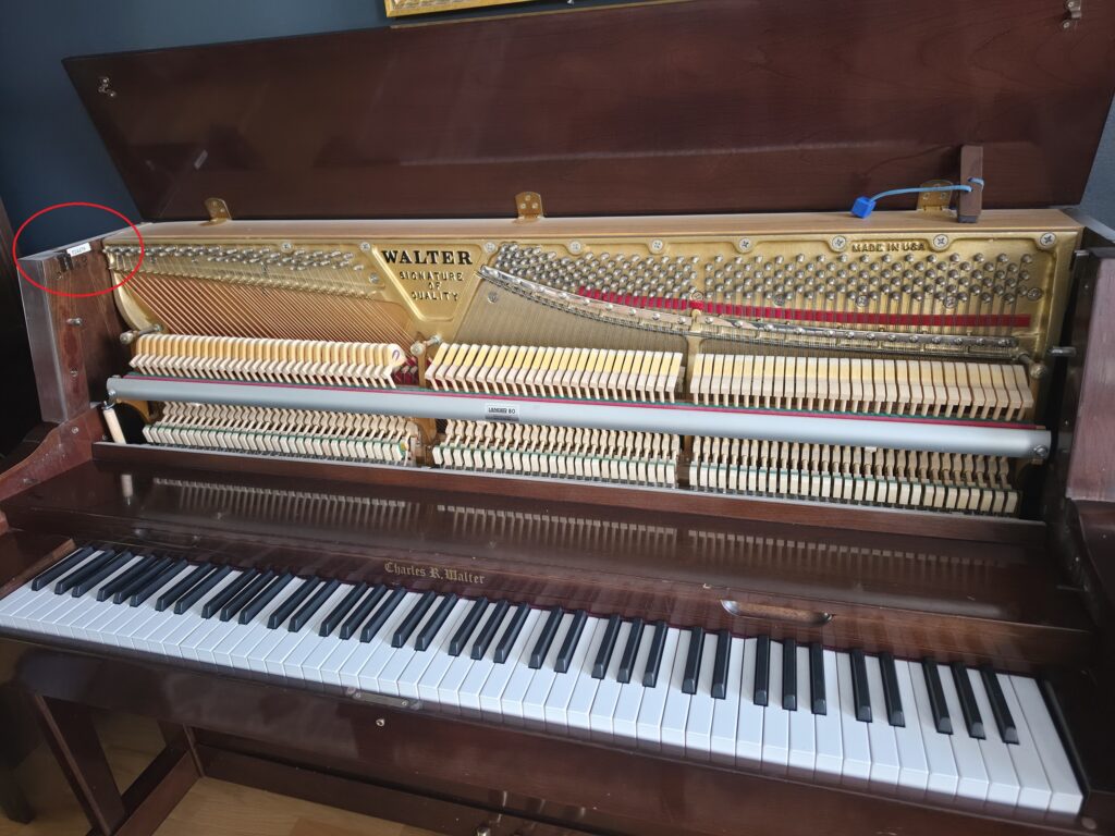 A Charles Walter upright piano with it's lid open and front removed.