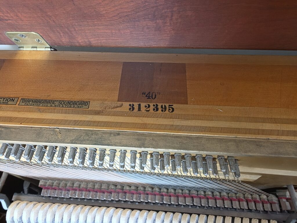 A Steinway & Sons console piano with the lid open, showing the location of the serial number.